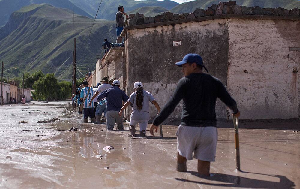 Volunteers walk with shovels on the way to help clear the mud