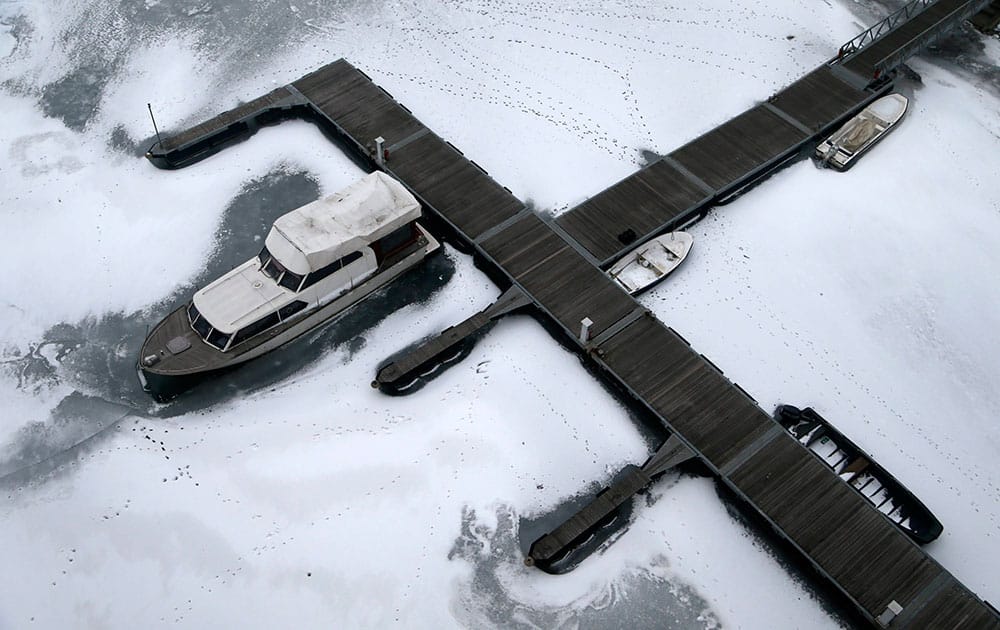 Boats are surrounded by ice and snow on a frozen section of the Sava river