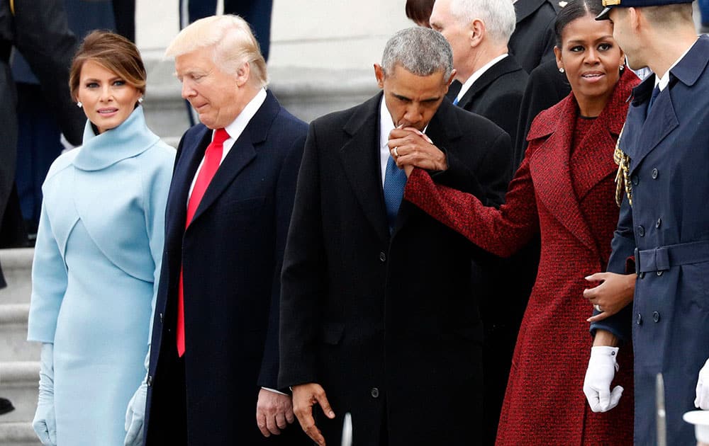 First lady Melania Trump stands with President Donald Trump as former President Barack Obama kisses the hand of his wife Michelle Obama