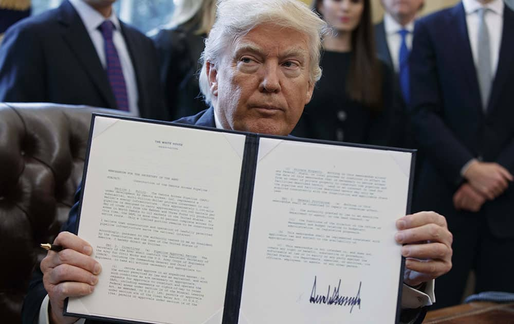 President Donald Trump shows off his signature on an executive order