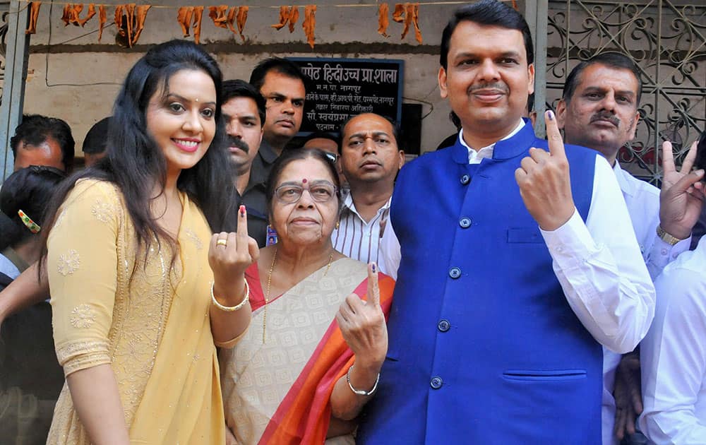 Maharashtra chief minister Devendra Fadnavis along with mother and wife Amruta showing ink marked fingures after casting their votes