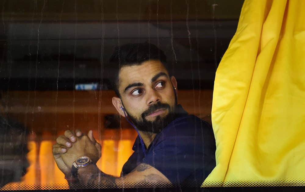 Virat Kohli looks on as he sits inside the team bus on his arrival in Bengaluru