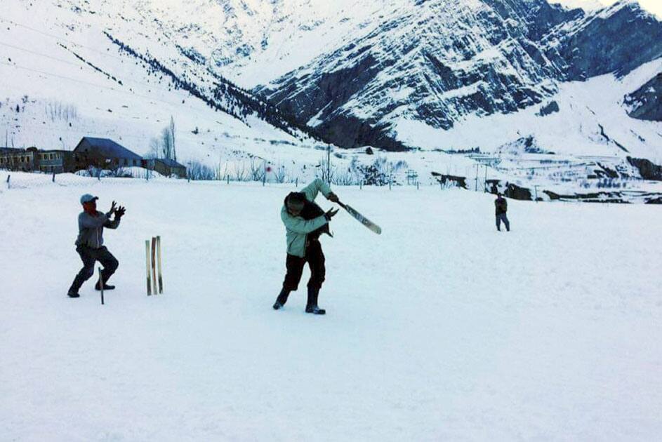 Boys play cricket at a snow covered field