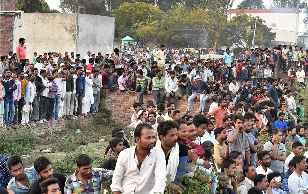 People gather near the site of the encounter between security forces and a suspected terrorist