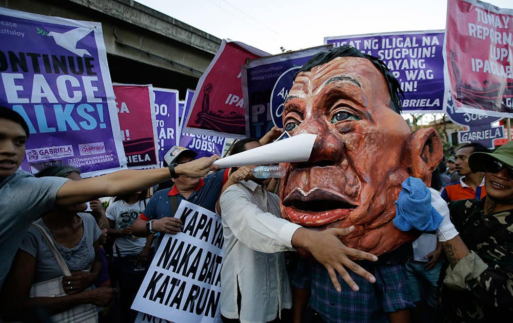 A protester reaches out to hit a big mask of Philippine President Rodrigo Duterte