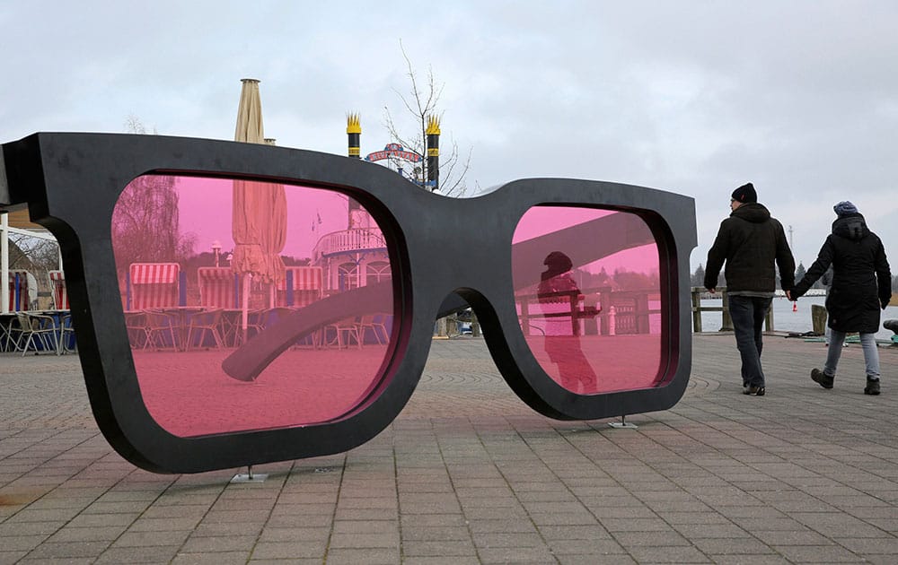 People pass giant pink sunglasses, the sculpture Sea Pink II by Marc Moser 