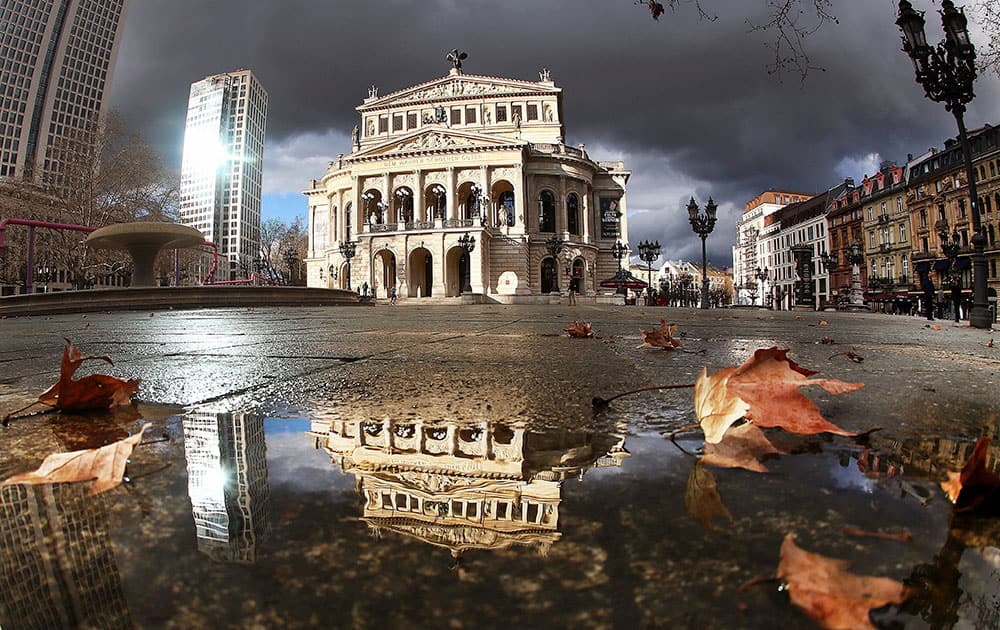 Dark clouds hang over the Old Opera which is spotlighted by the sun