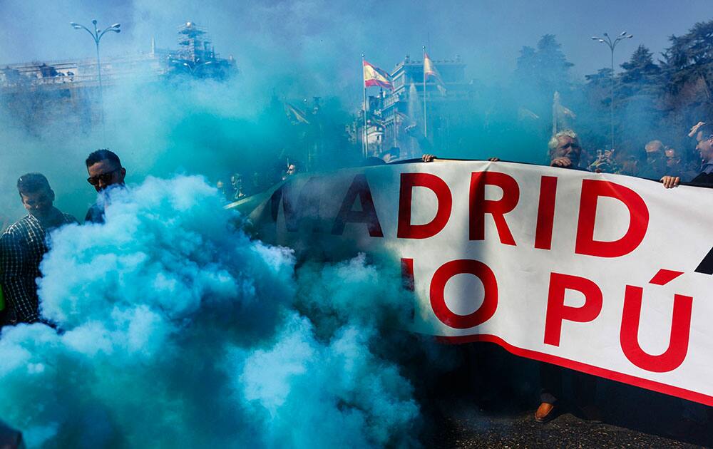 Blue smoke covers taxi workers as they protest blocking the main city artery