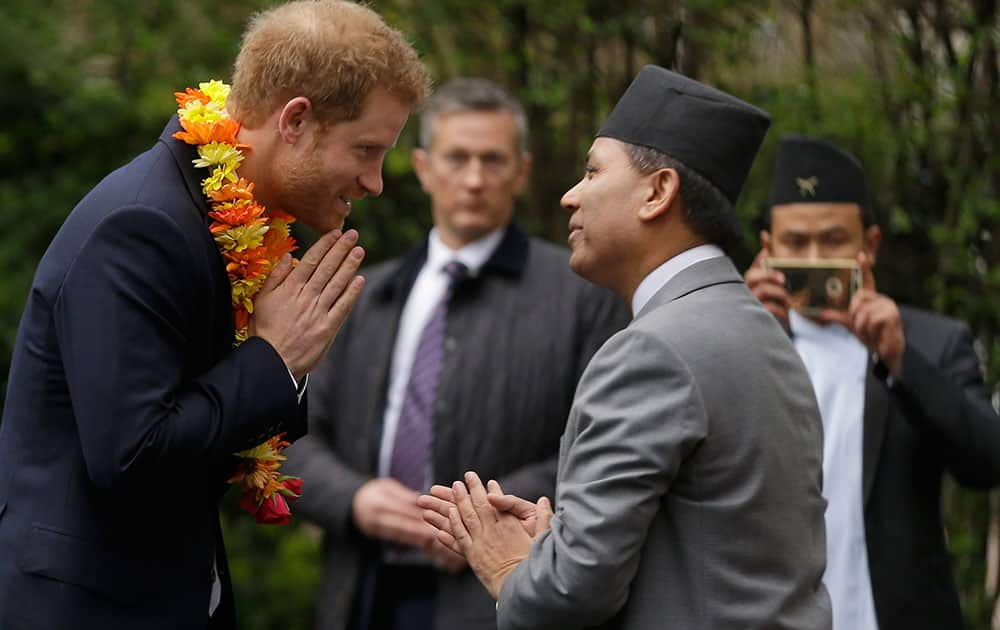 Prince Harry smiles as he is presented with a floral garland to wear as he arrives at the Nepalese Embassy