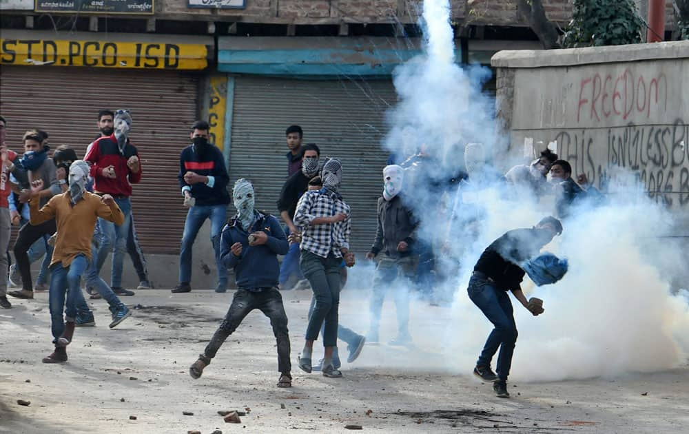 A protester throws back tear gas shell toward police during a clash