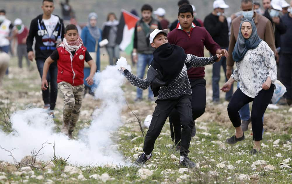 A Palestinian boy throws back teargas canister during clashes with Israeli forces