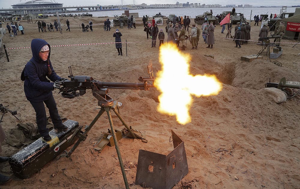 A girl shoots a World War II machine gun armed