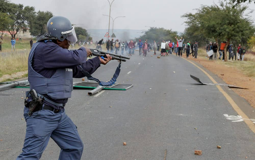 A policeman fires rubber bullets at protesters in Johannesburg