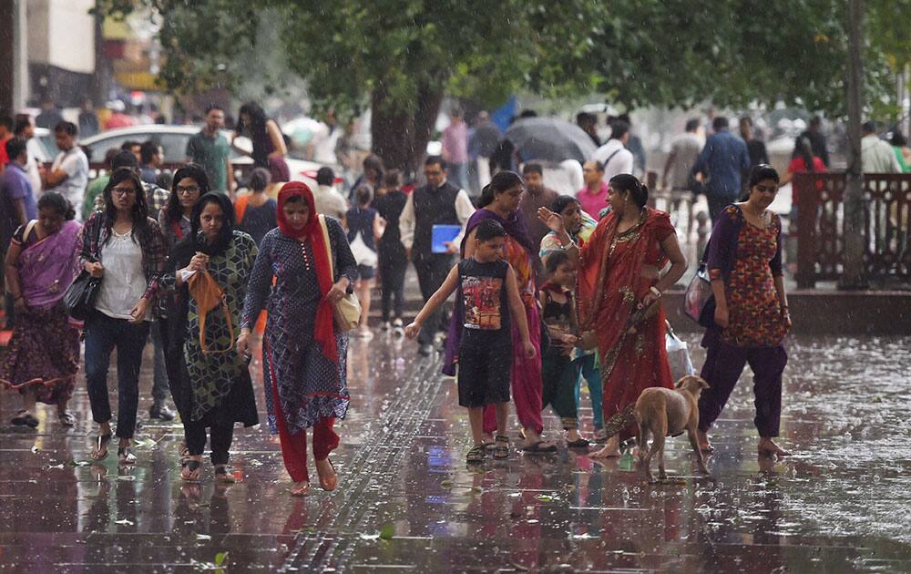 People walk at Connaught Place area during rains