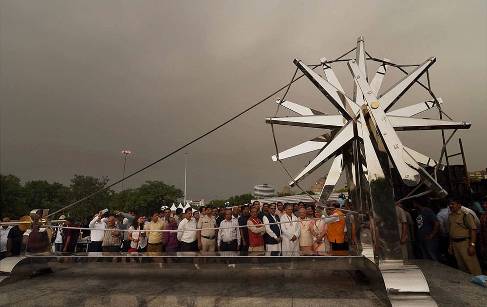 Kalraj Mishra, Mahesh Sharma and others standing near a larger-than-life steel Charkha