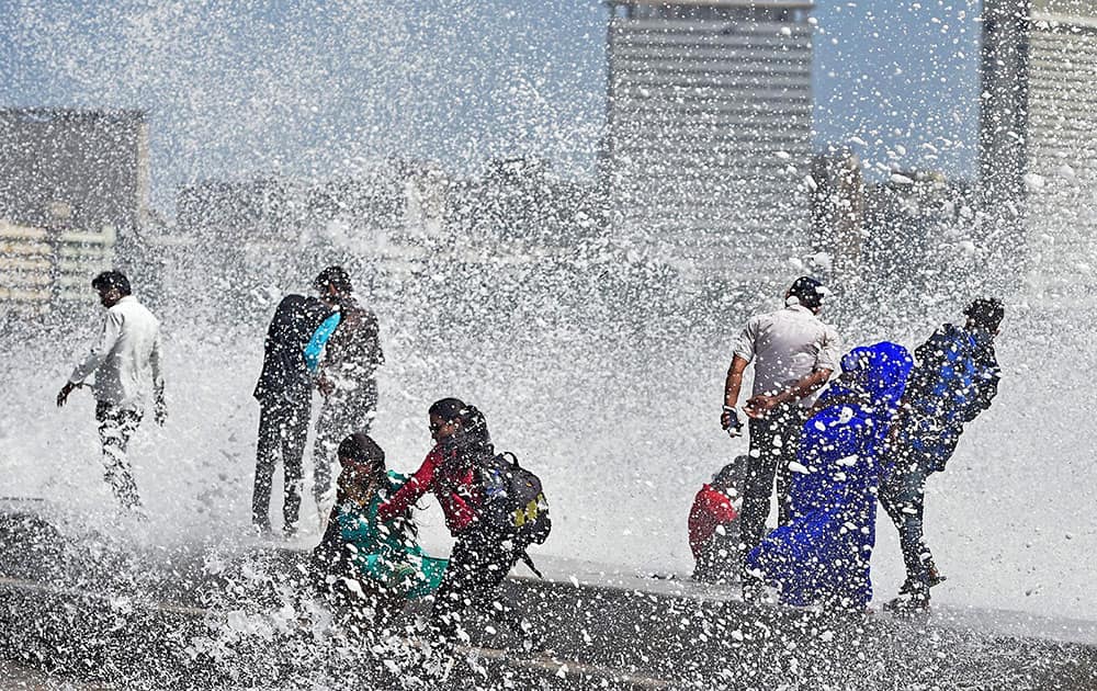 People enjoy a high tide at the Marine Drive