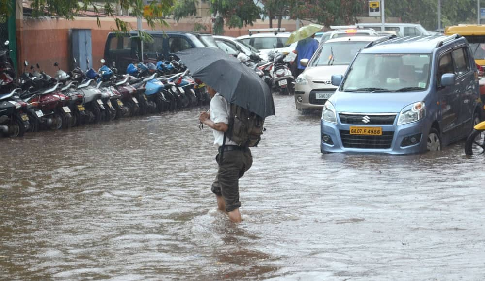 A man wades through water logged streets of Panaji