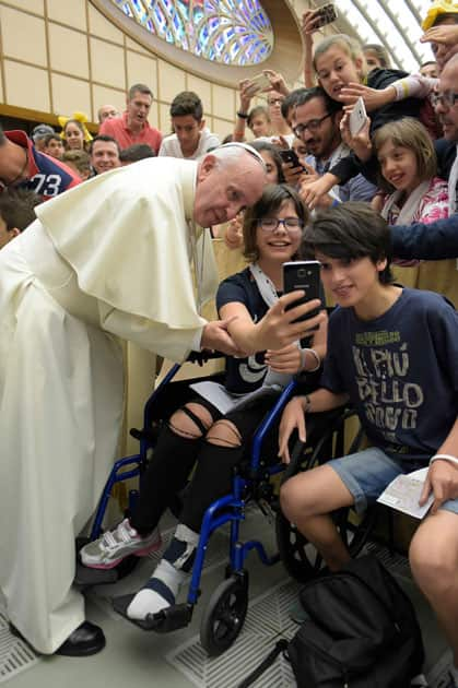 Pope Francis poses for a picture with youths