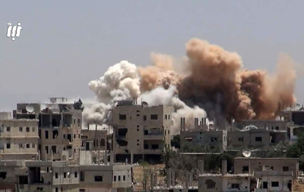 smoke rising over buildings that were hit by Syrian government forces bombardment