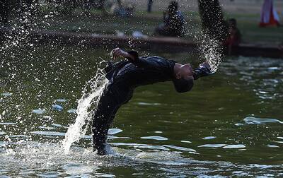 A boy beats the heat in a pond near India Gate