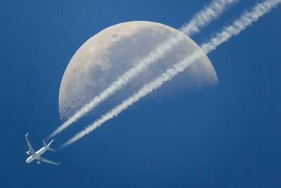A commercial airplane flies past the moon