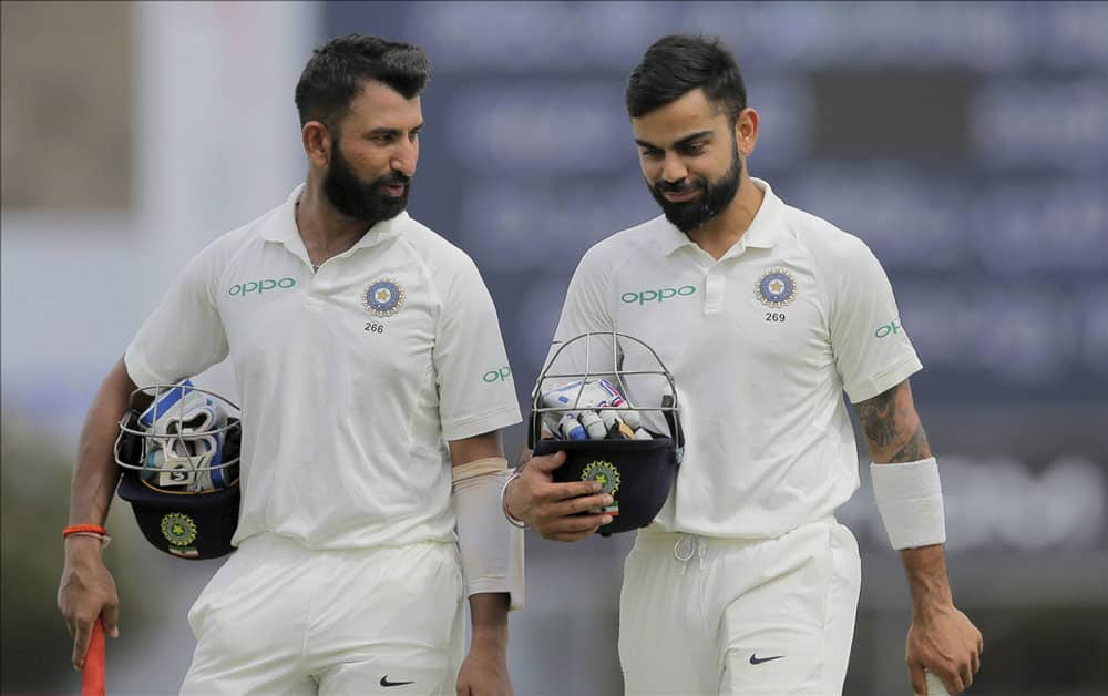 captain Virat Kohli and Cheteshwar Pujara walk off