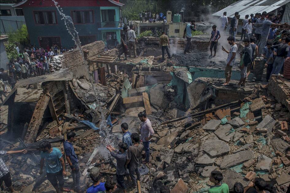 Villagers standing on the debris of a house which was destroyed