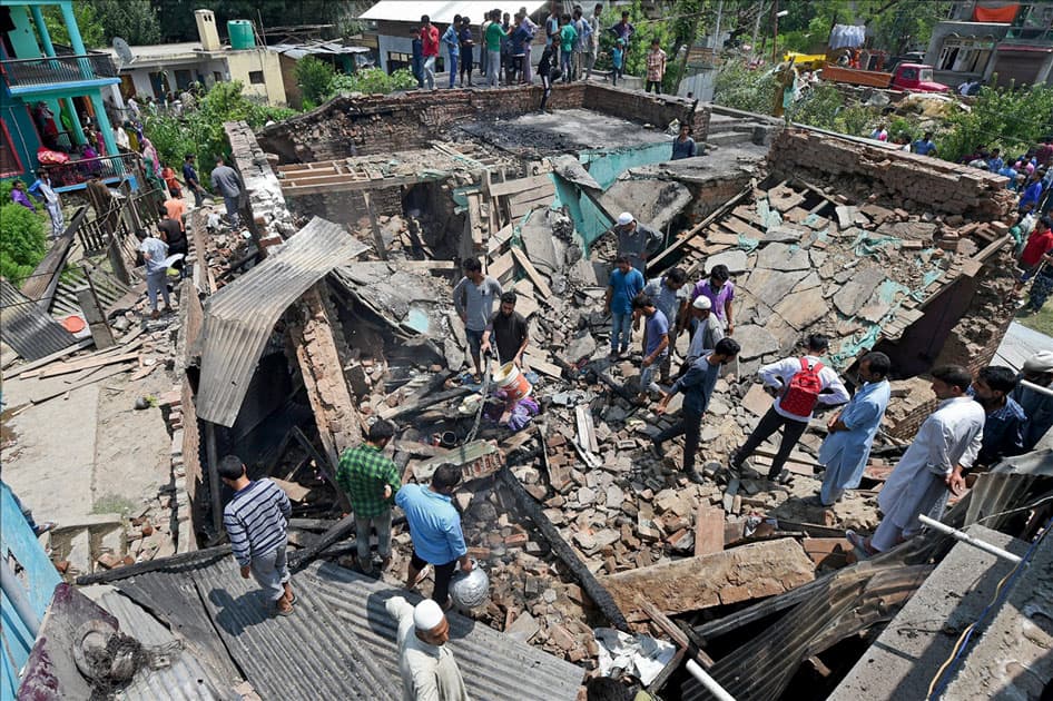 Villagers standing on the debris of a house which was destroyed