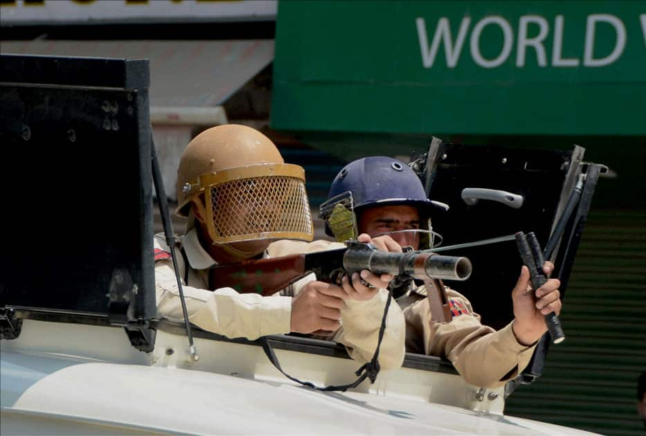 A policeman aims to fire teargas shell to disperse stone throwing youth