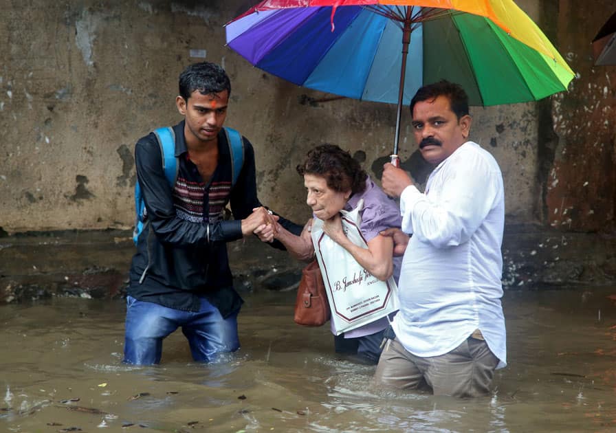 A woman is helped to move through a water-logged road