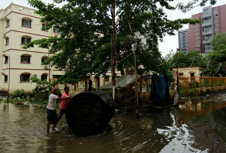 Men push a water tank through partially flooded street