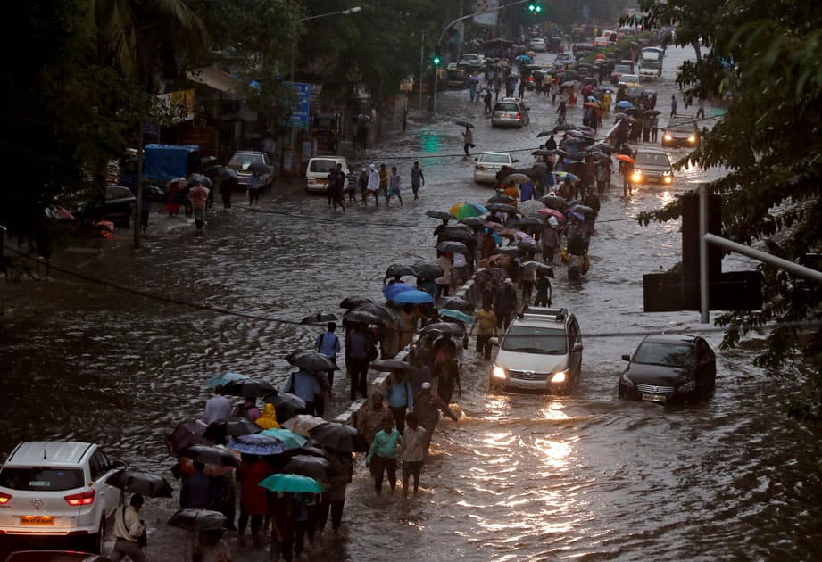 Commuters walk through water-logged roads after rains