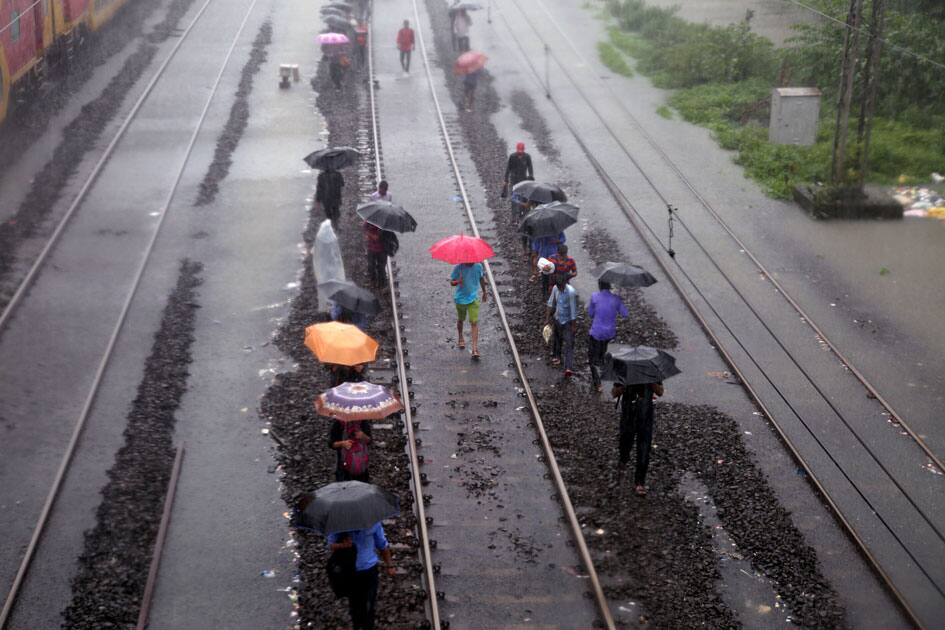 People walk on water-logged railway tracks during rains