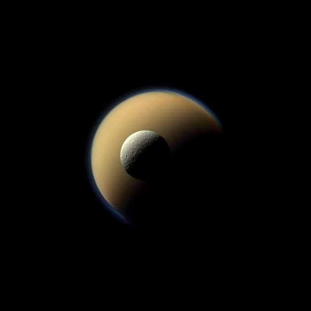 Saturn's largest and second largest moons, Titan and Rhea, appear to be stacked on top of each other in this true-color scene from NASA's Cassini spacecraft