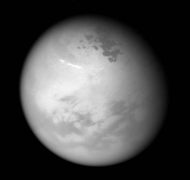 NASA's Cassini spacecraft sees bright methane clouds drifting in the summer skies of Saturn's moon Titan, along with dark hydrocarbon lakes and seas clustered around the north pole