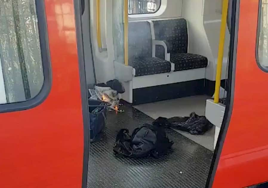 Personal belongs and a bucket with an item on fire inside it, are seen on the floor of an underground train carriage