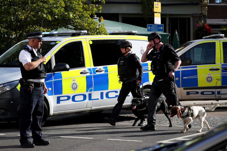 Police officers and sniffer dogs walk near Parsons Green tube station in London