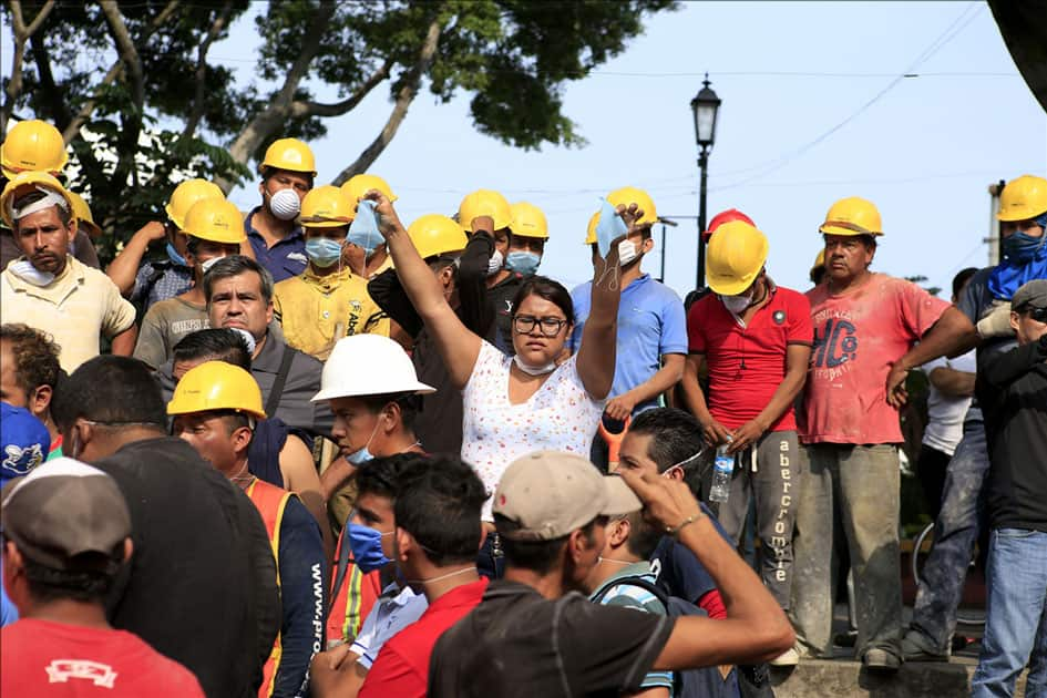 A woman distributes masks in front of a collapsed building after an earthquake in Cuernavaca City, Morelos State, Mexico.