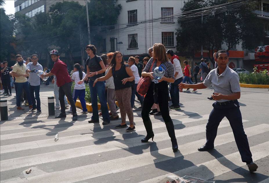 People move bottles of water during rescue efforts on a collapsed building after an earthquake in Mexico City, capital of Mexico