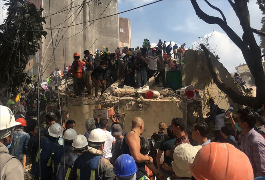 people searching for victims in a collapsed building after an earthquake in Mexico City, capital of MexicoPeople work on the roof of a collapsed building after an earthquake in Mexico City, capital of Mexico.