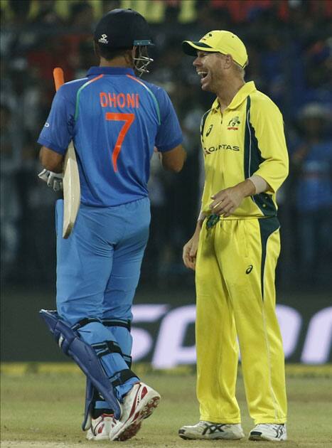 India's MS Dhoni shares a light moment with Australia's David Warner after winning the third ODI cricket match against Australia at Holkar Cricket Stadium in Indore