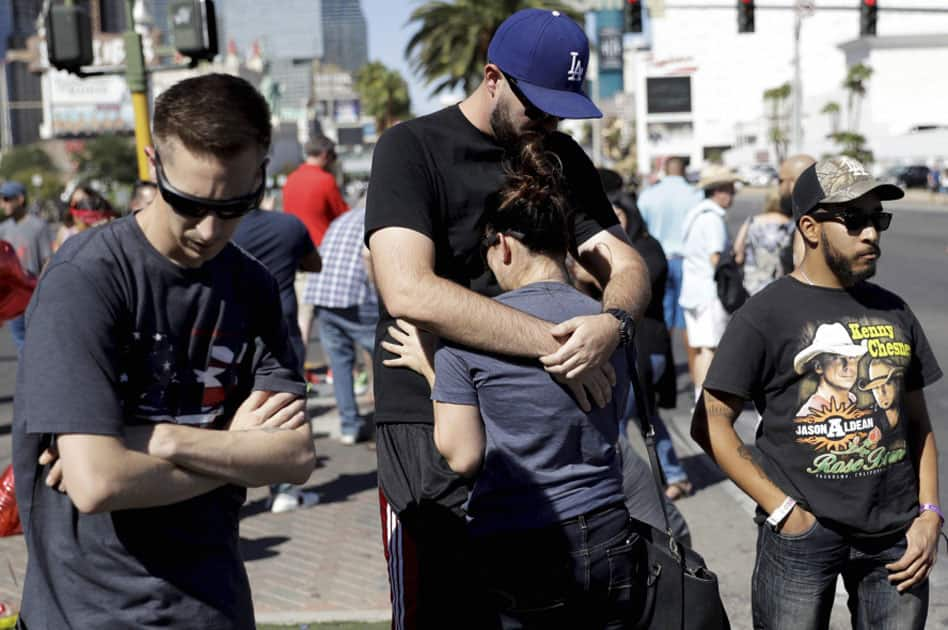 Reed Broschart, center, hug his girlfriend Aria James on the Las Vegas Strip in the aftermath of a mass shooting at a concert in Las Vegas.