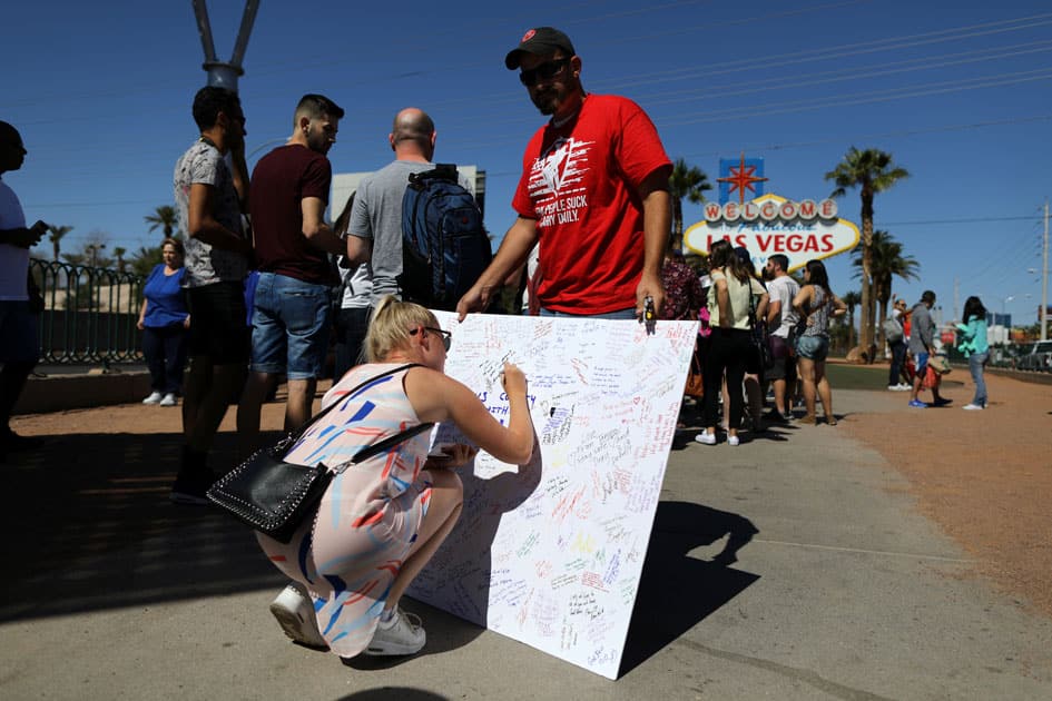 A woman signs a memorial board on the Las Vegas Strip for victims of the Route 91 music festival mass shooting next to the Mandalay Bay Resort and Casino in Las Vegas.