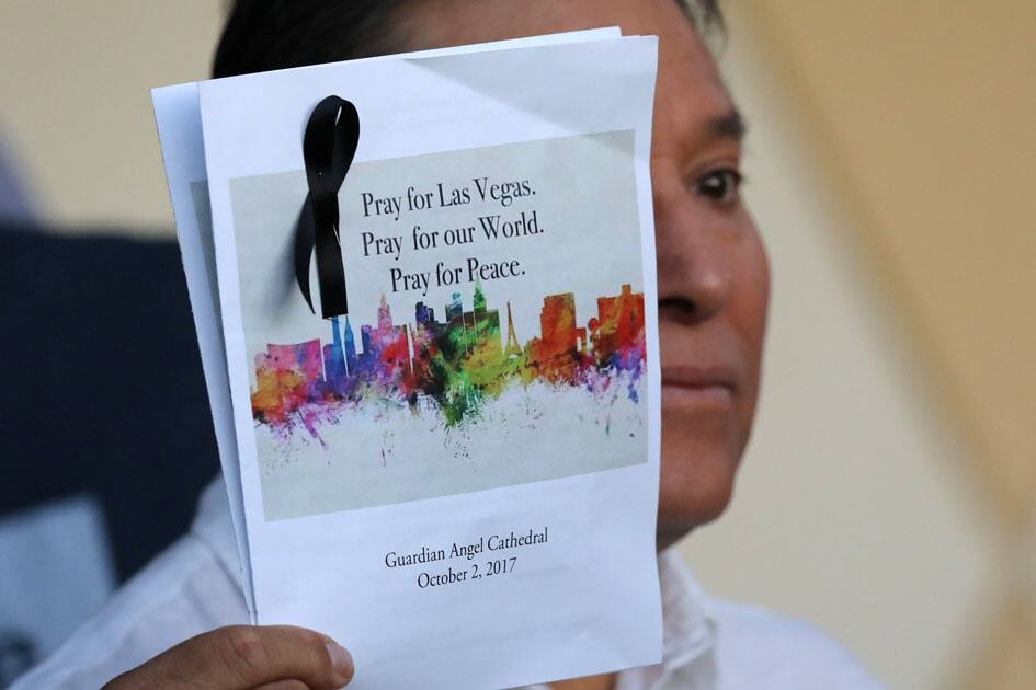 A man holds a program after an interfaith memorial service for victims of the Route 91 music festival mass shooting outside the Mandalay Bay Resort and Casino in Las Vegas.