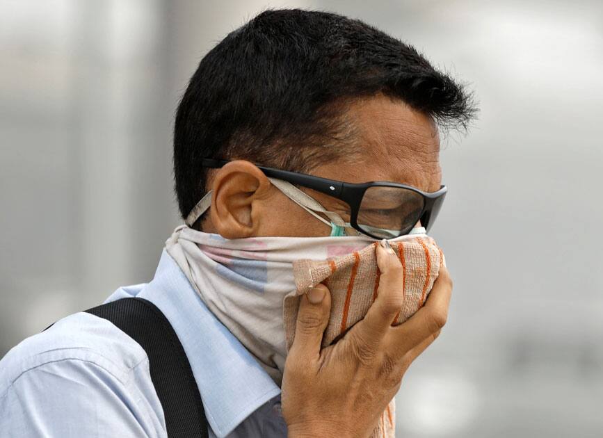 Man covers his face as he walks to work in Delhi.