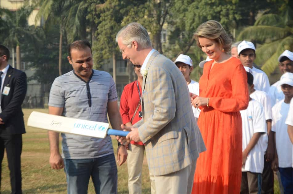 Belgium's King Philippe, Queen Mathilde and former Indian cricketer Virender Sehwag play cricket with under privileged children during an event hosted by UNICEF in Mumbai.