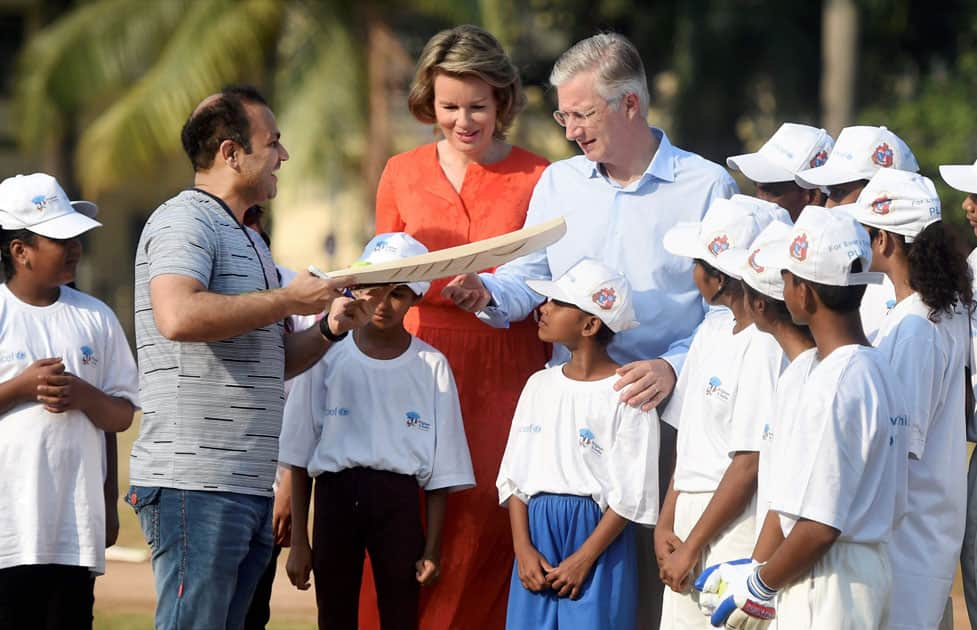 Former cricketer Virender Sehwag presents a bat to the Belgian Royal couple King Philippe and Queen Mathilde after a cricket clinic at the Oval maidan, in Mumbai.