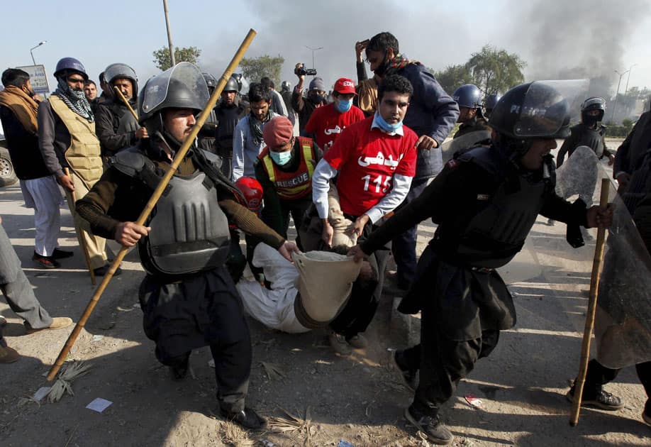 Pakistani police officers carry an injured protester during a clash in Islamabad, Pakistan.