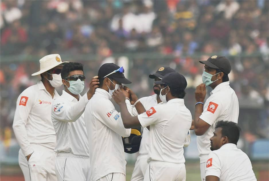 Sri Lankan players wear anti-pollution masks on the field, as the air quality deteriorates during the second day of their third test cricket match against India in New Delhi.