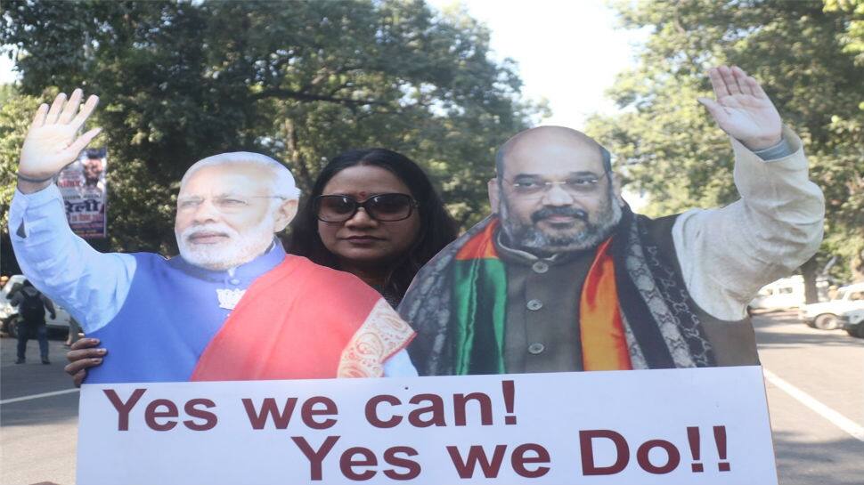 A party worker celebrates with the standies of Prime Minister Narendra Modi and BJP chief Amit Shah in New Delhi